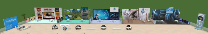 Image of a virtual event space featuring various sponsor booths lined against a wall. The booths have colorful banners with branding. There are black chairs and tables in front of each booth, and a "Help Desk" sign is visible on the left.